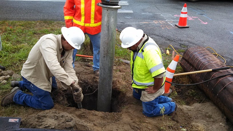 PUD employees digging out a hole around a power pole