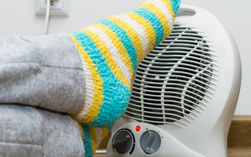 Person putting their feet with fuzzy socks on a space heater