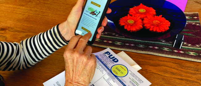 Over the shoulder, woman switching to paperless bill paying on her phone