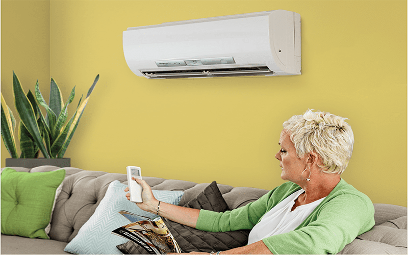 Woman sitting on couch with ductless heat pump above