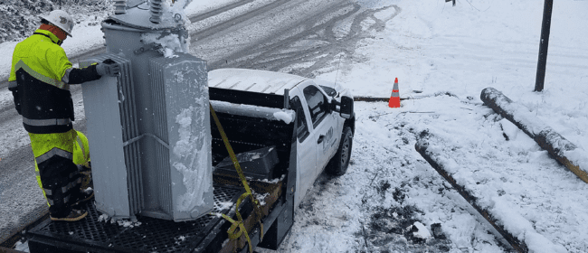 PUD crew hoisting equipment from truck in the snow in Quilcene