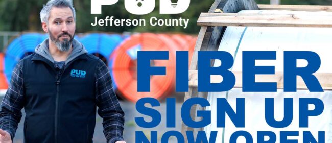 PUD employee standing beside large rolls of fiber optic cable with the text Fiber Sign Up Now Open. Used as a thumbnail for video.