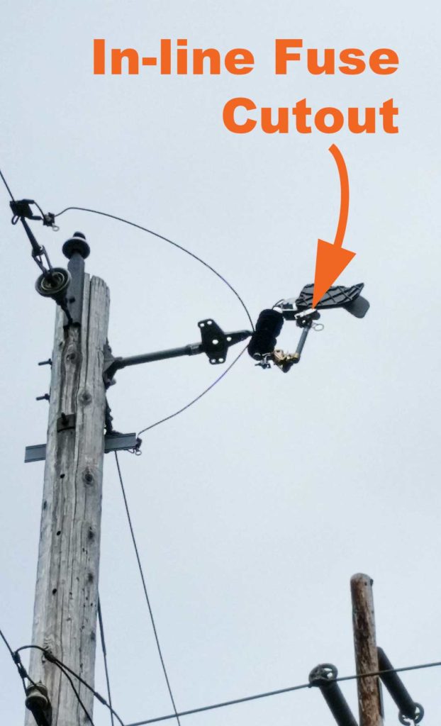 Images showing a cutout fuse on top of a distribution pole.