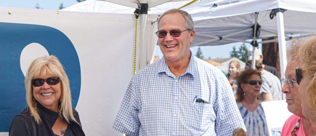General Manager Kevin Streett smiling and talking with customers at the pUD booth during an outdoor event.