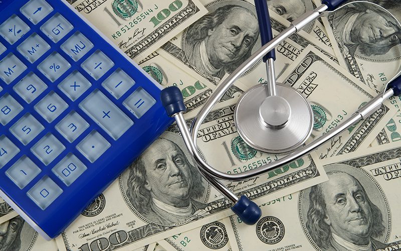 Blue calculator and stethoscope on money background