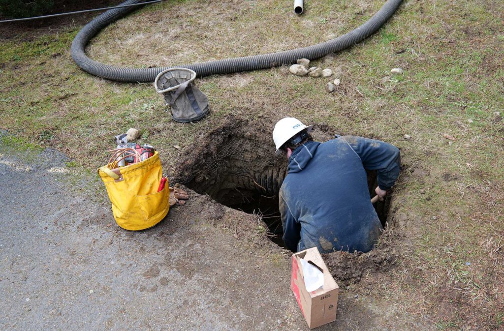 Line crew member hand-digs the remaining material to access the underground line fault.