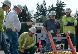 John Spain, NW Safety Service trainer (white shirt, left) covers vacuum pump run time for clearing the practice vault with the PUD team.