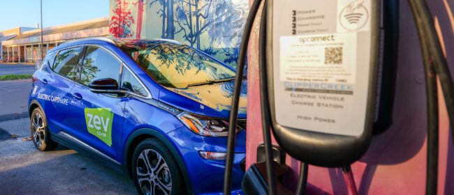 Blue ZEV Co-op car next to a charging station
