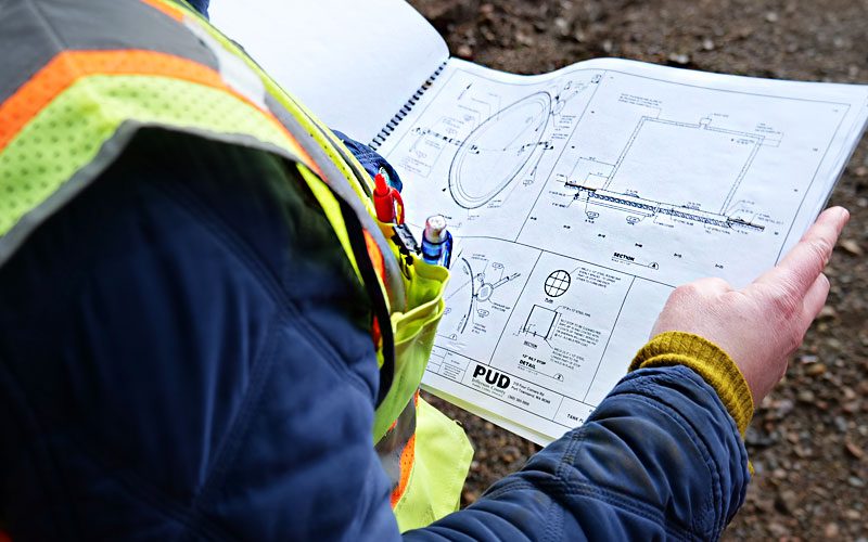 A PUD employee holding a set of water tank engineering plans.