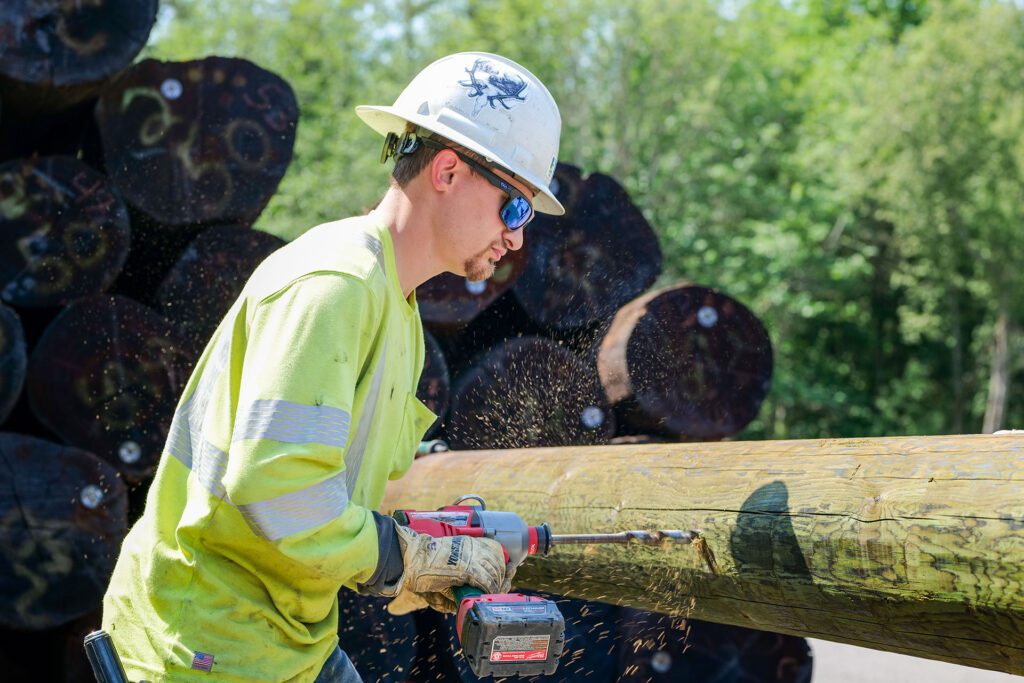 PUD employee drilling a hole in a horizontal utility pole in the PUD yard