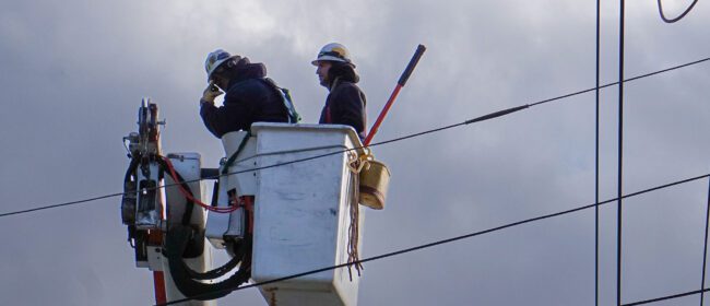 Two linemen in a line truck bucket.