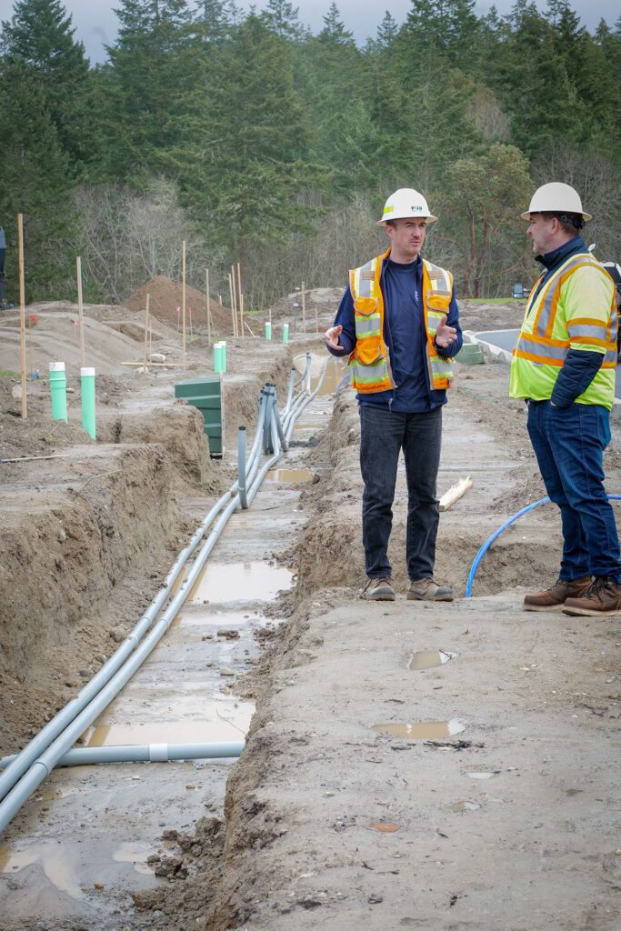 PUD Staking Engineer, Russell Miller (left) and PUD Safety Manager, Jeff Dodd survey the open joint-use trench at the Madrona Ridge project in Port Townsend.