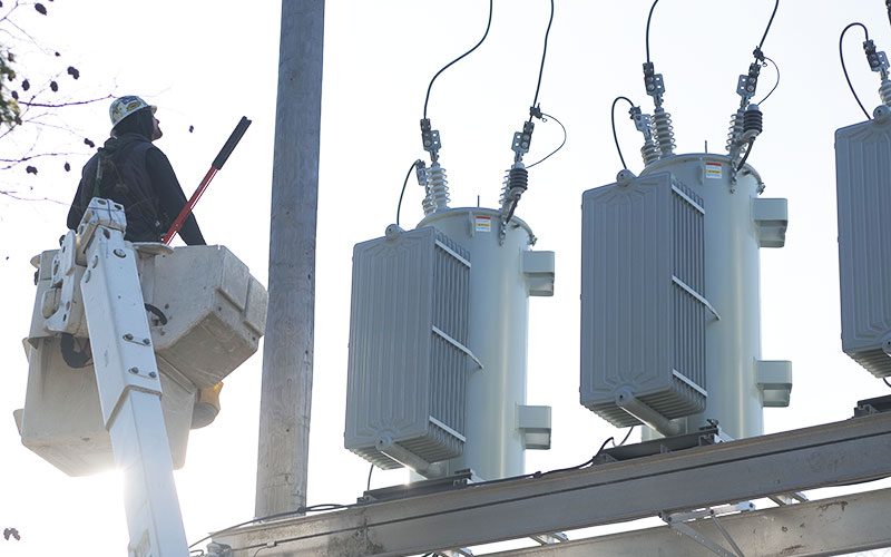 A PUD employee in a bucket lift looking at a substation