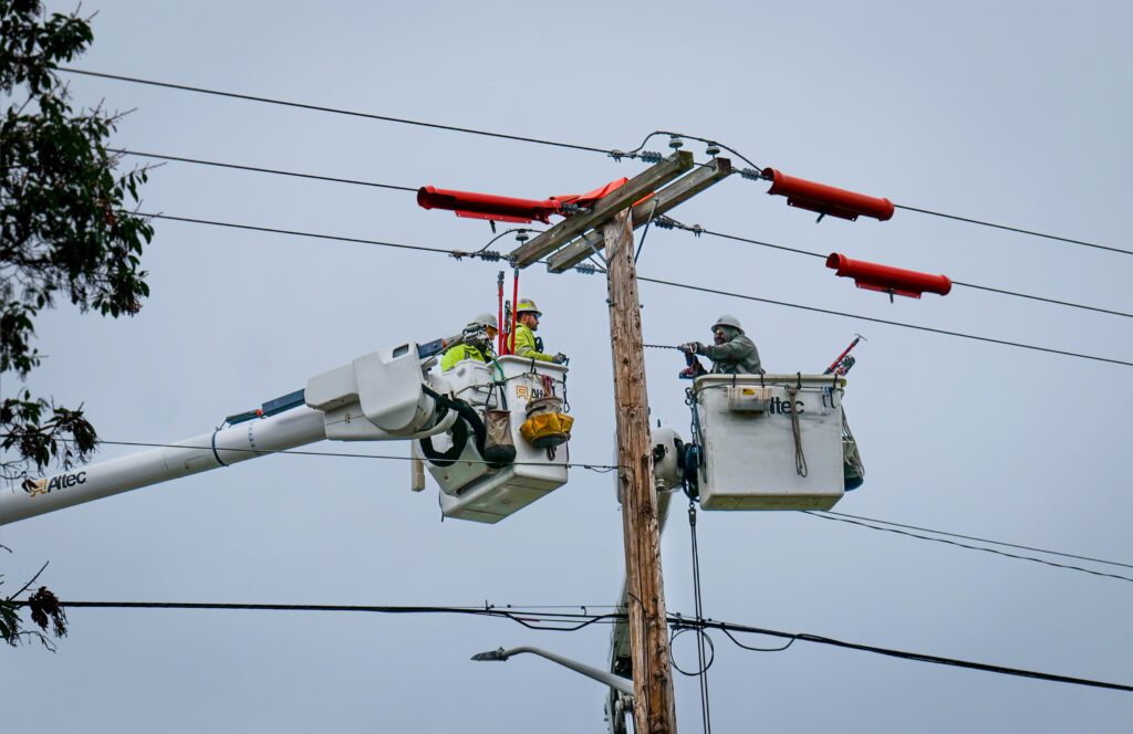 A lineman drills a hole through a utility pole to mount the switch.