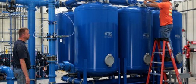 Two PUD employees working on water tanks