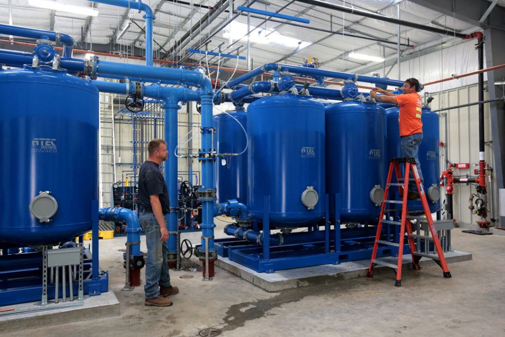 Two PUD employees working on water tanks